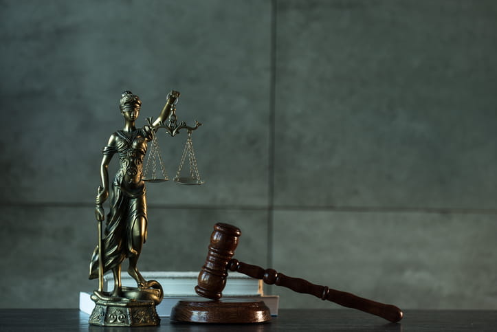 A Lady Justice statue next to a gavel and two books on a personal injury attorney's desk. 