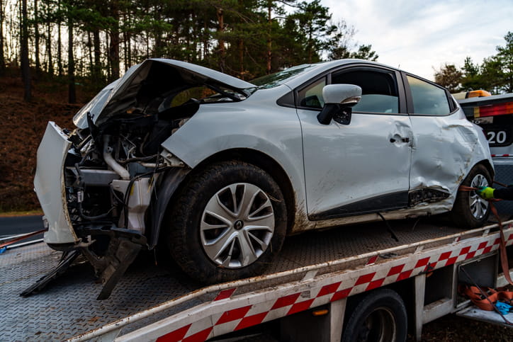 A severely damaged vehicle being towed away after a car accident.