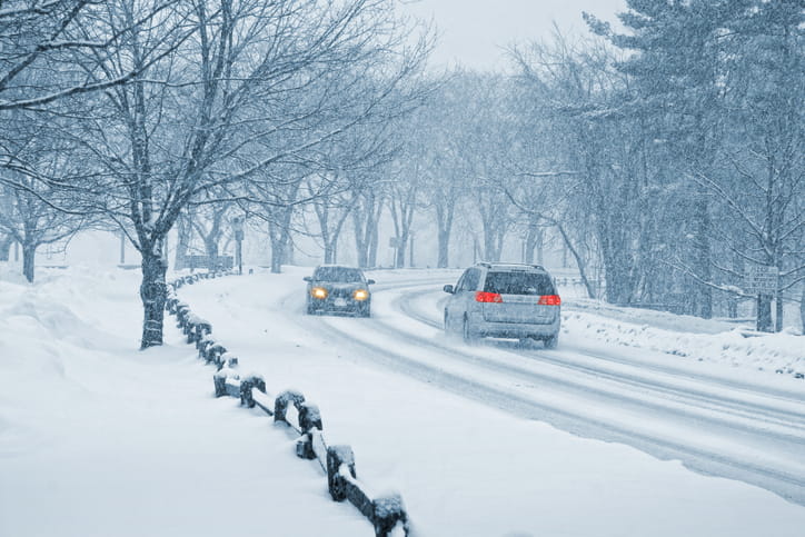 Two vehicles driving past one another in a snowstorm.